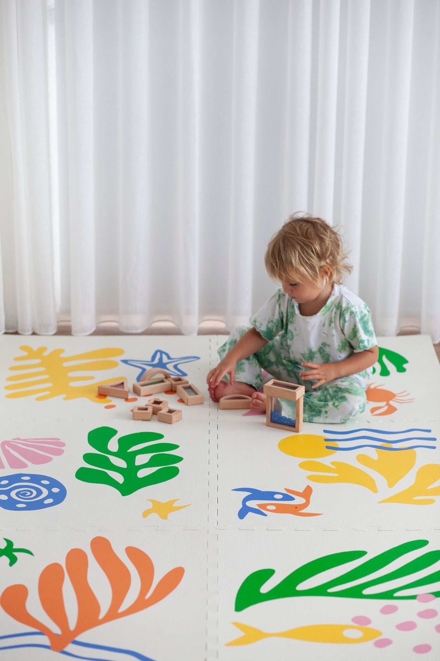 Toddler sitting and playing on a colourful foam play mat