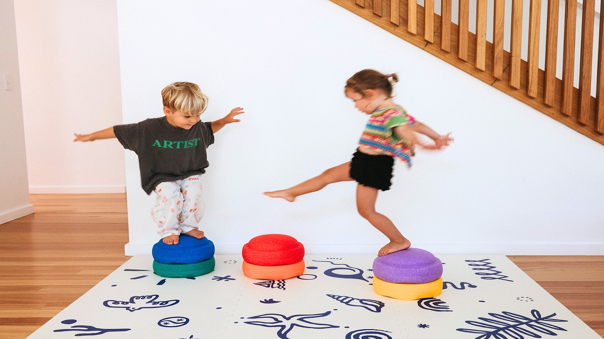 Children playing together walking on stepping stones on coloured foam play mat with interlocking tiles